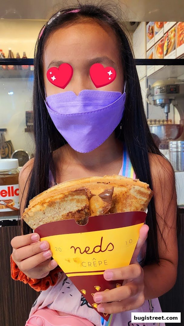 A young girl holds a delicious crepe from Neds Crepe.