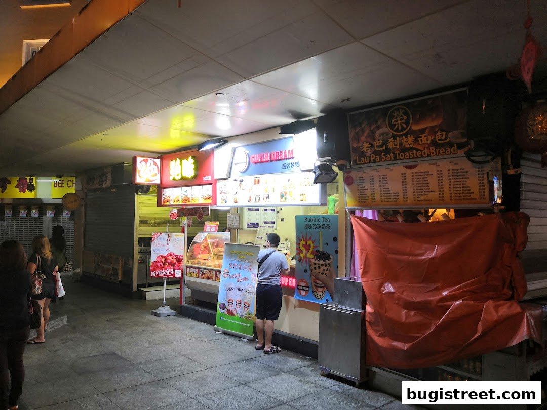 A row of food stalls, including Super Dream, with illuminated signs and menus.