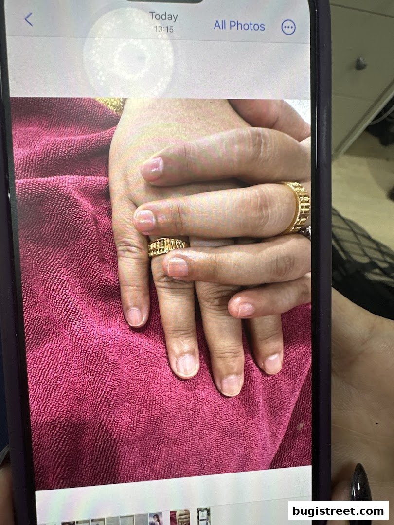 Close-up of hands with natural nails and gold rings on a pink towel.