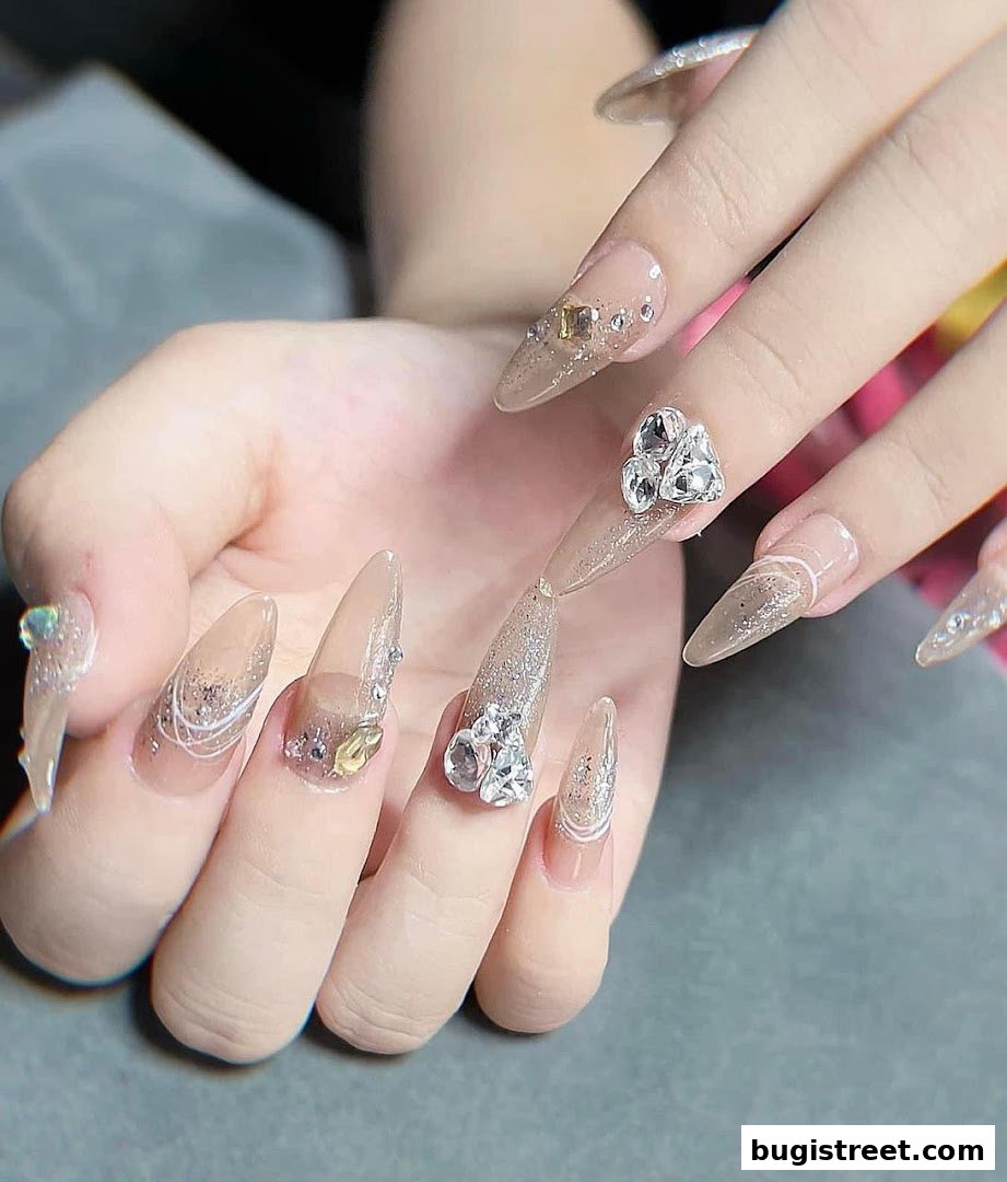 Close-up of hands with elaborate, sparkling acrylic nails adorned with rhinestones.