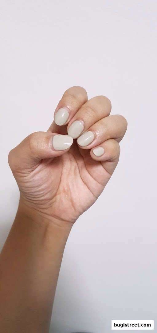A hand with neatly manicured nails painted in a subtle, neutral beige color.