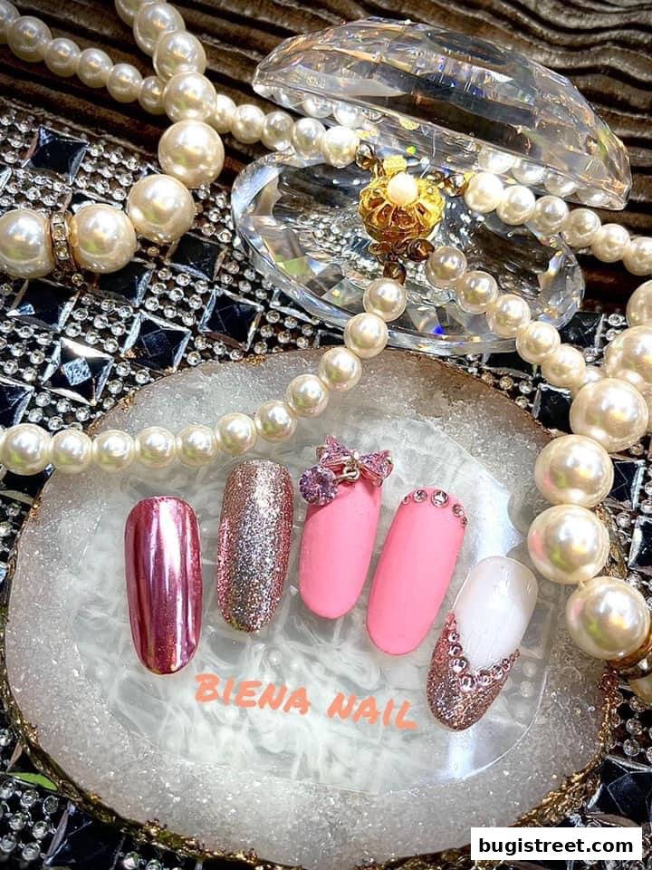 A display of five beautifully decorated artificial nails with pearls and crystals.