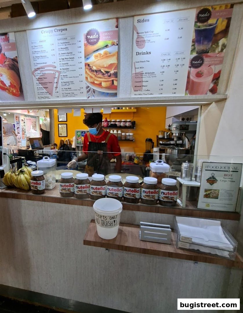 A counter display with a menu, Nutella jars, and a staff member preparing crepes.