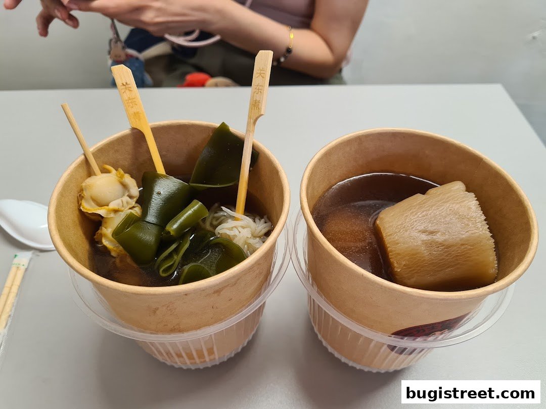 Two cups of Oden soup with various ingredients like scallops, kelp, and daikon radish.