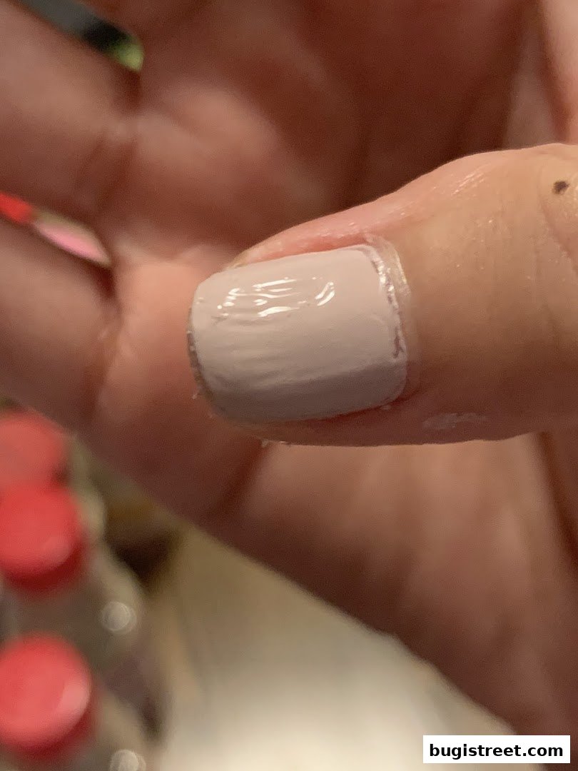 Close-up of a person's hand with a freshly painted light pink nail.