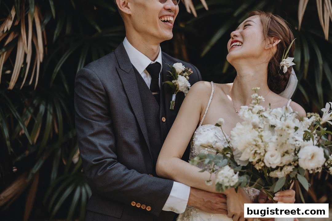 A joyful couple, a bride and groom, embracing amidst lush greenery.