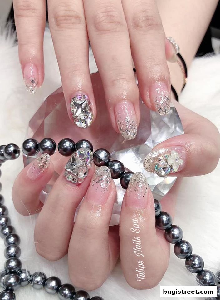 Close-up of hands with elaborately decorated nails featuring glitter and rhinestones.