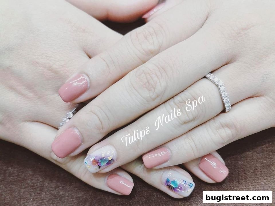 Close-up of hands with elegant pink nail polish and artistic accent nails.