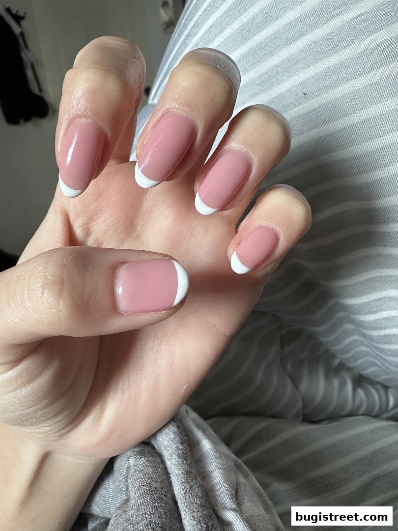 A close-up shot of a hand with perfectly manicured French tip nails.