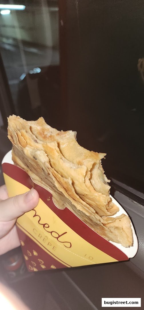 A hand holds a delicious crepe from Neds Crepe & Coffee, with a bite taken out.