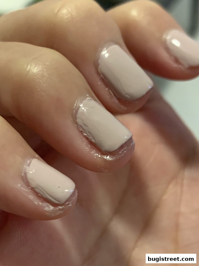 Close-up of a hand with neatly painted light beige nails.