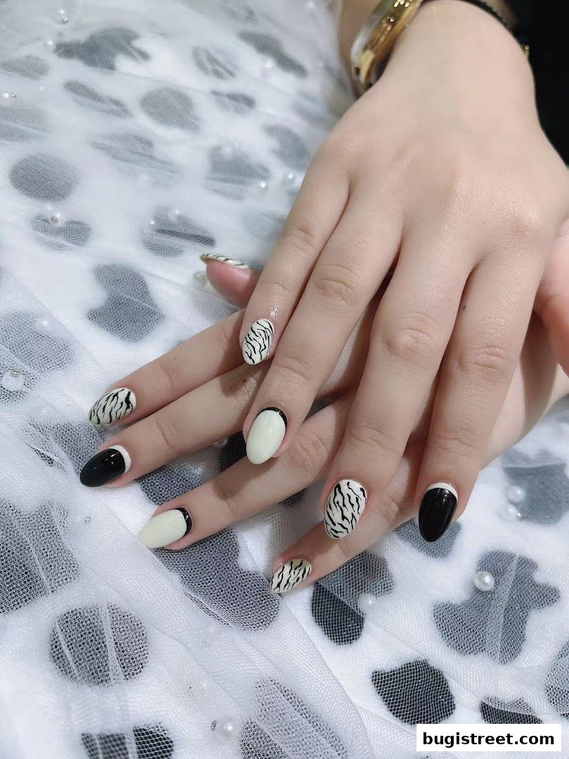 A close-up of hands with stylish black, white, and tiger-striped nail designs.
