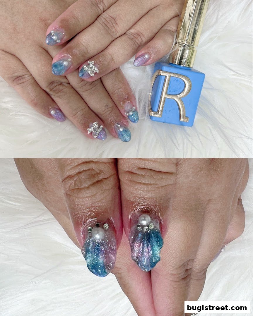 Close-up of hands with intricate, sparkling blue and purple nail art, featuring pearls and rhinestones.