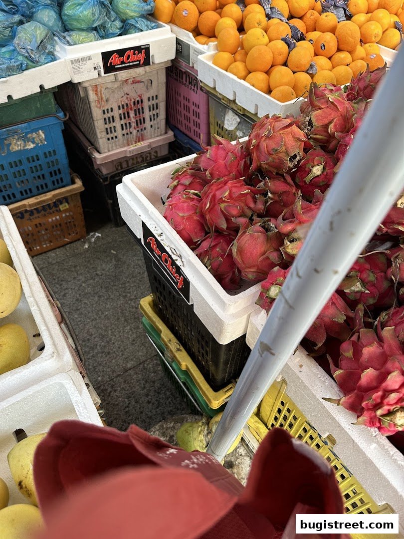 A vibrant display of fresh fruits, including dragon fruit, oranges, and other produce, at a street market stall.