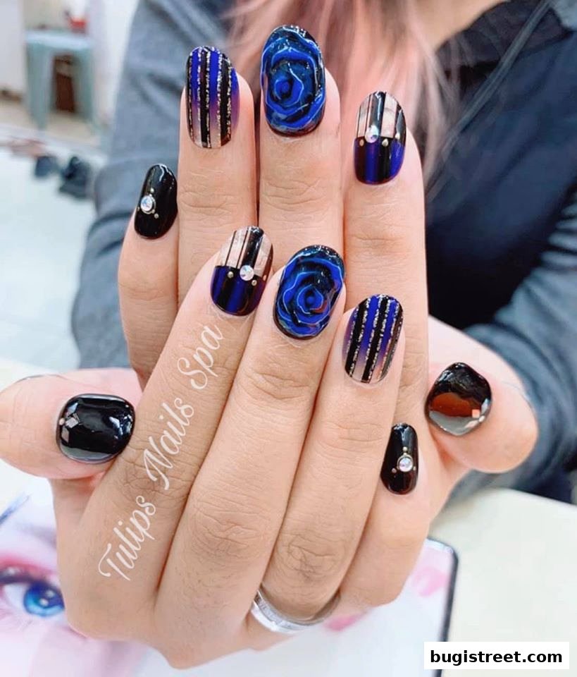 Close-up of hands with intricately designed blue rose and striped nails with rhinestones.