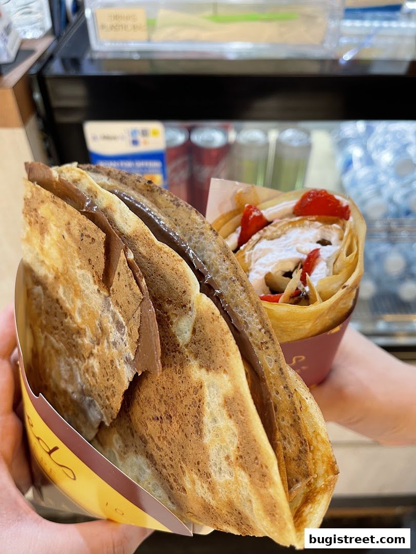 Two delicious crepes, one filled with chocolate and the other with strawberries and cream.