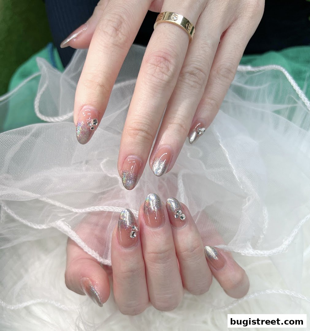 Close-up of hands with elegant, sparkling nail art featuring glitter and rhinestones.