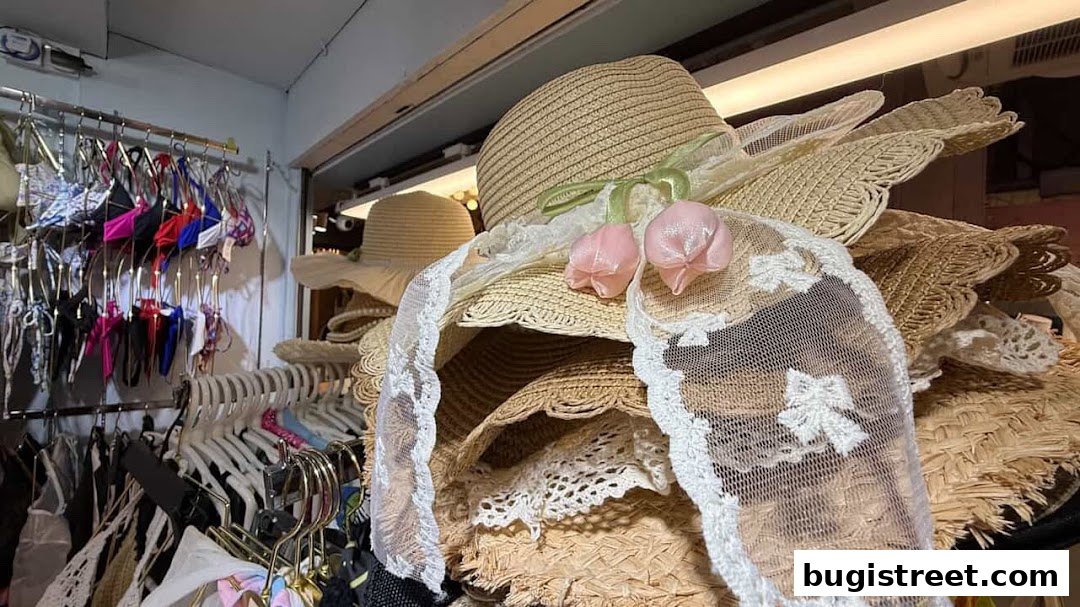 A display of straw hats with decorative ribbons and lace, alongside hanging garments.