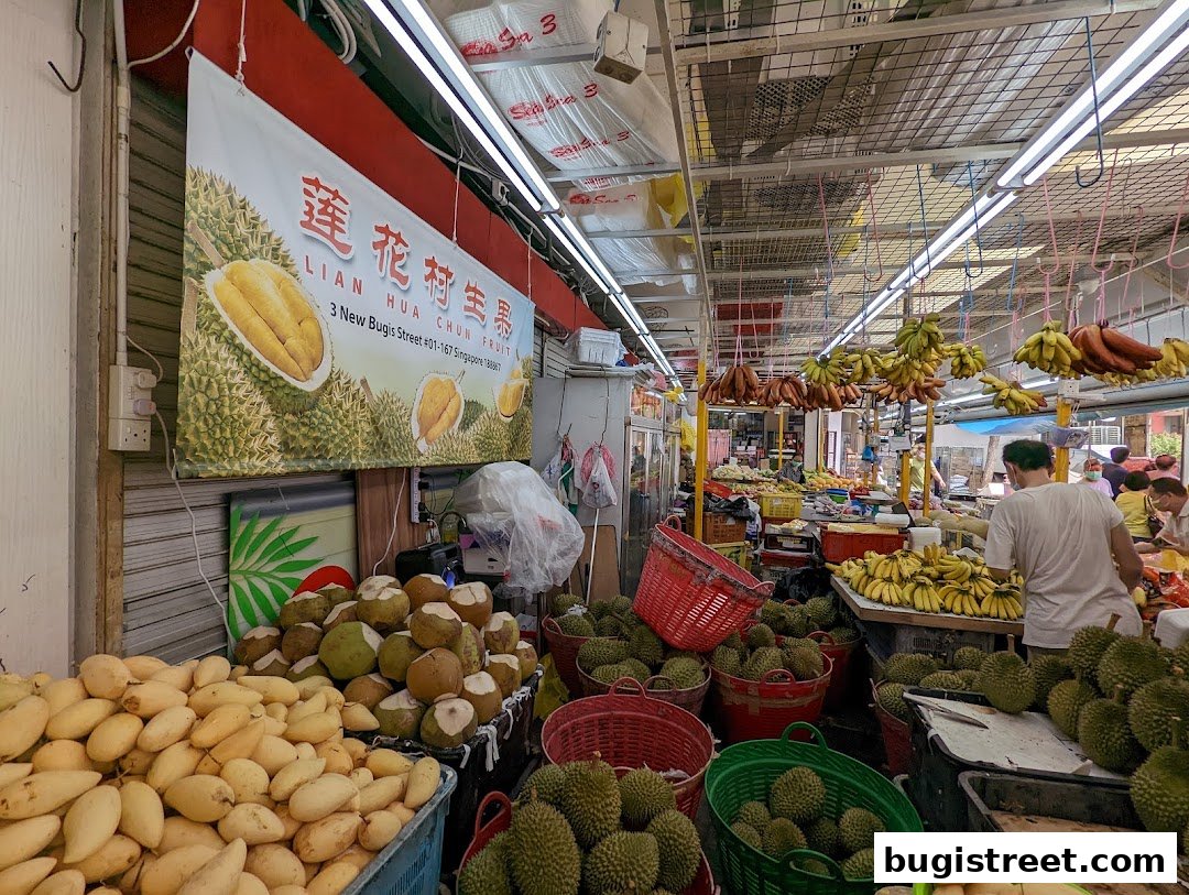 A fruit stall displaying a variety of fresh fruits including durians, mangoes, and bananas.
