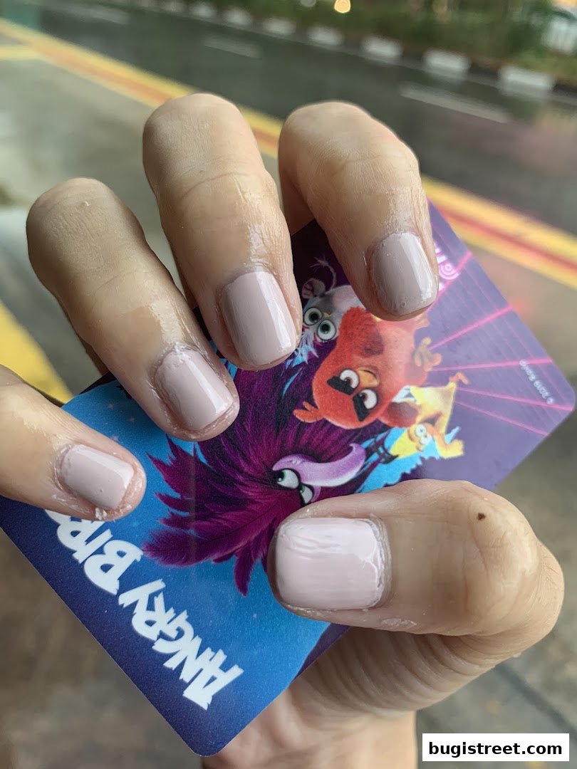 A close-up of hands with light pink and nude polished nails holding an Angry Birds themed card.