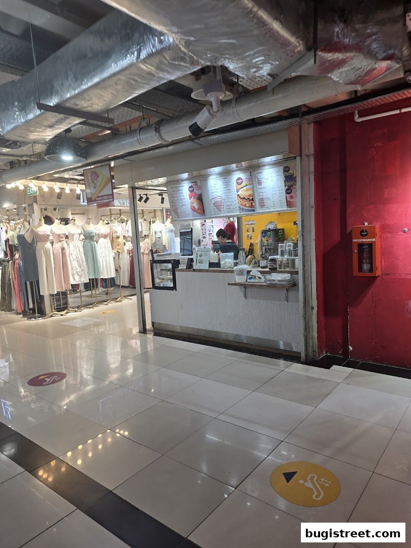 A view of Neds Crepes & Coffee shop with a menu board and display of clothing next door.