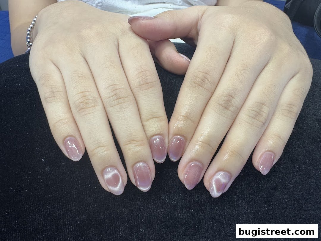 Close-up of a person's hands with beautifully manicured, glossy, light pink nails.