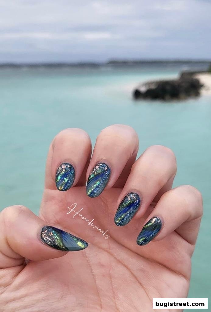 A close-up of a hand with beautifully designed blue and green glitter nails.