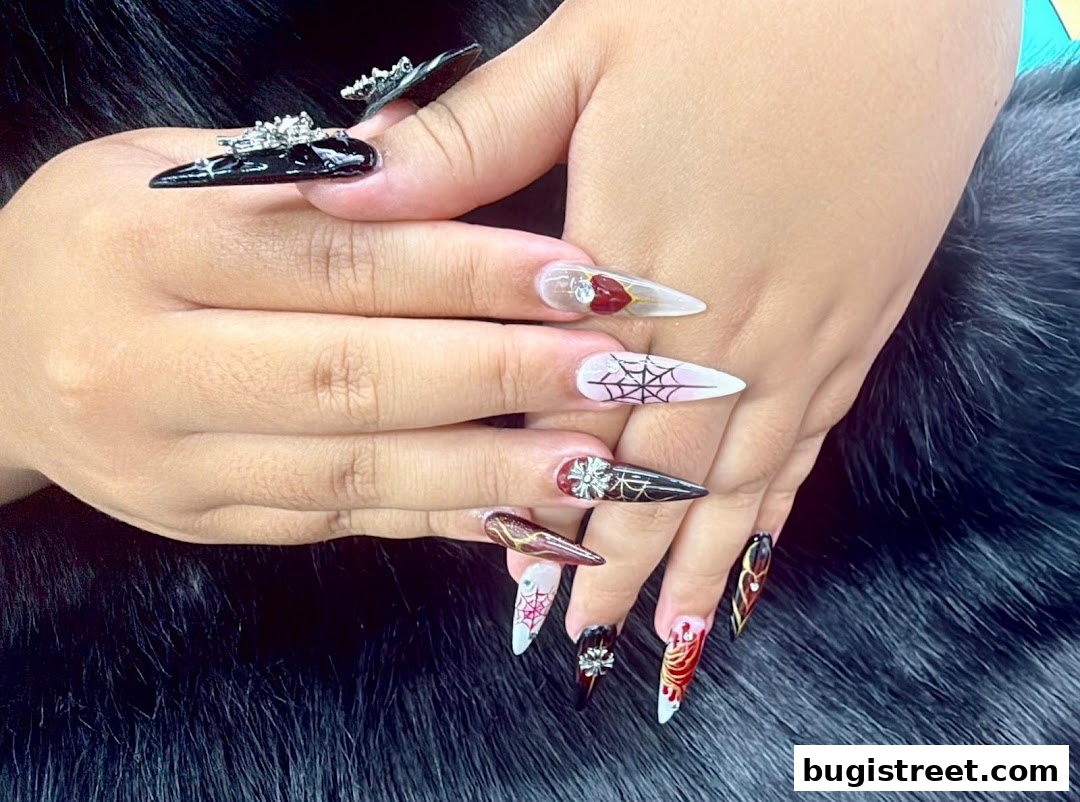 A close-up of hands with elaborately designed stiletto-shaped nails featuring intricate patterns and embellishments.