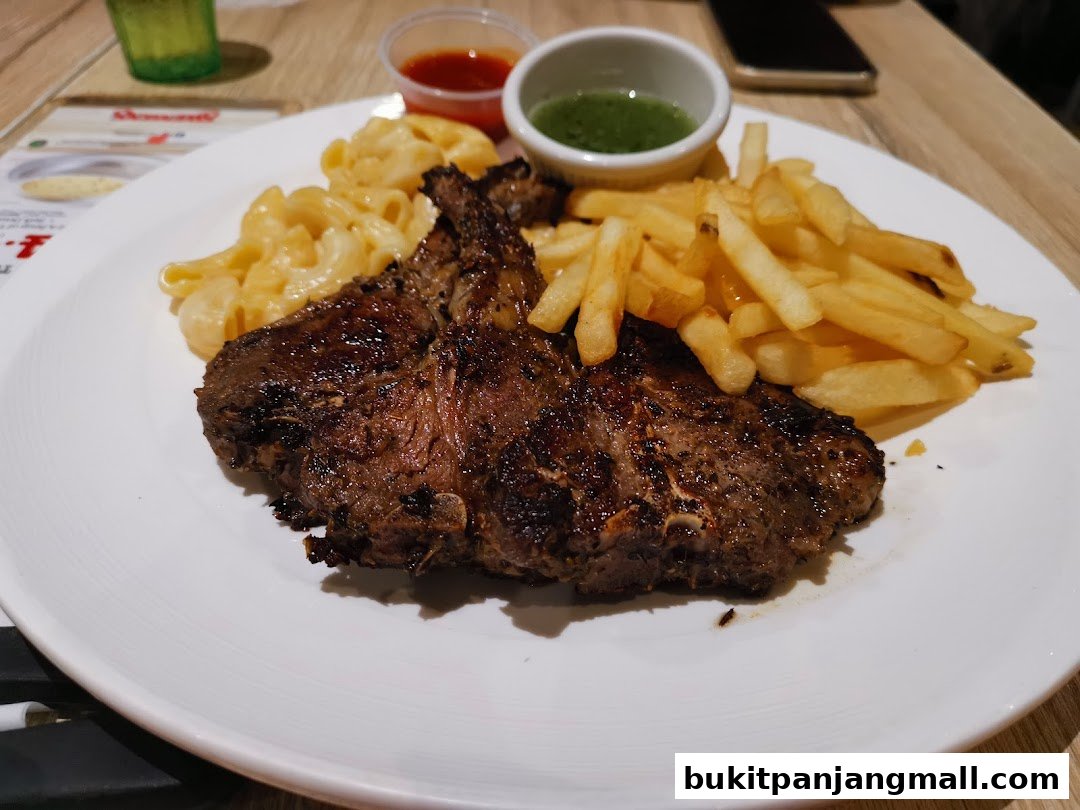 A plate of steak, french fries, and macaroni and cheese with dipping sauces.