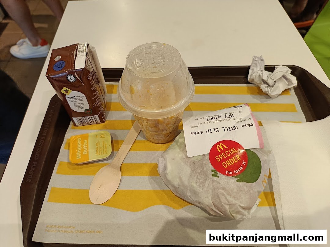 A tray of McDonald's food including a burger, drink, whipped butter, and chocolate milk.