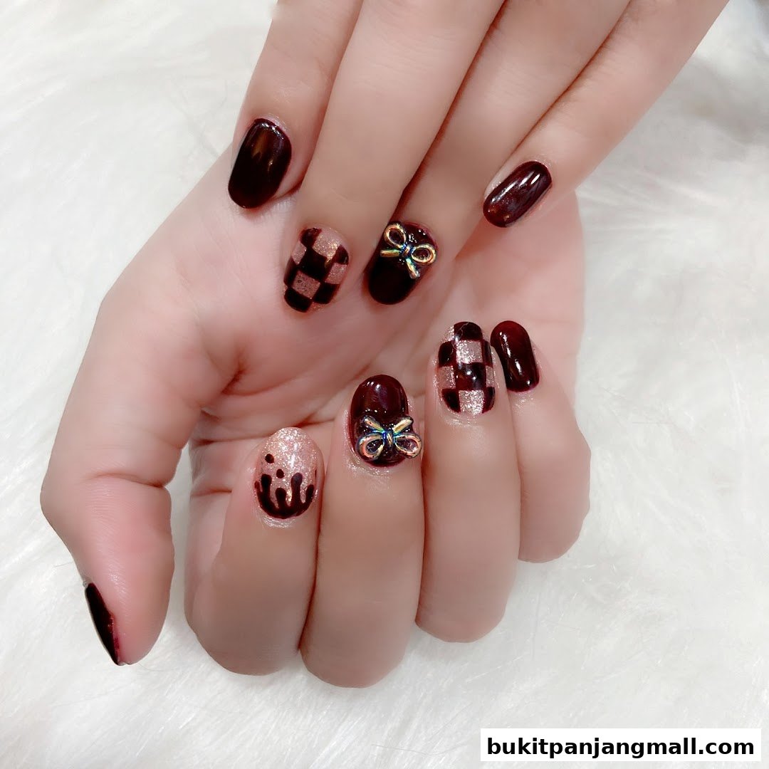 A close-up of a hand showcasing intricate nail art with a dark red polish, checkered pattern, and bow embellishments.