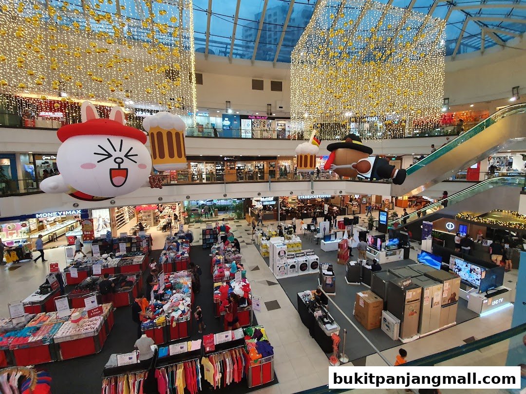 A bustling shopping mall interior with festive decorations and various retail displays.
