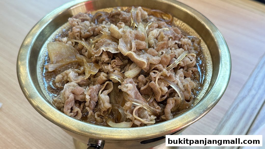 A close-up of a steaming bowl of beef and onions, likely a Korean dish.