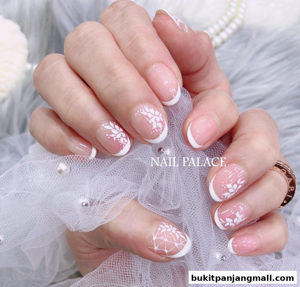 Close-up of hands with elegant French manicures featuring white floral nail art.