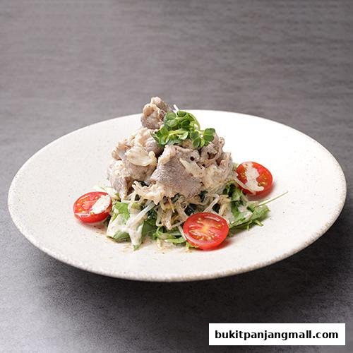 A close-up of a salad with thinly sliced meat, greens, and cherry tomatoes on a white plate.