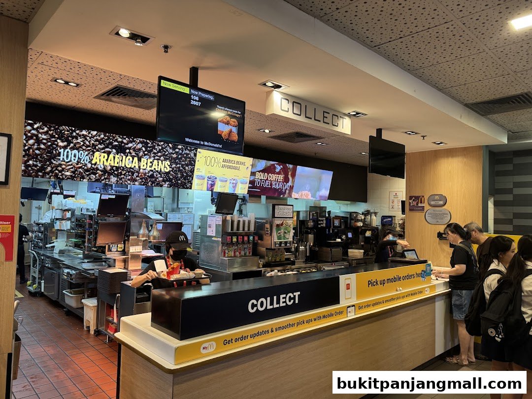 Inside a McDonald's restaurant showing the counter, staff, and customers picking up orders.
