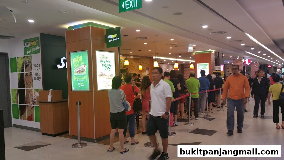 A Subway restaurant with a queue of customers waiting to order.