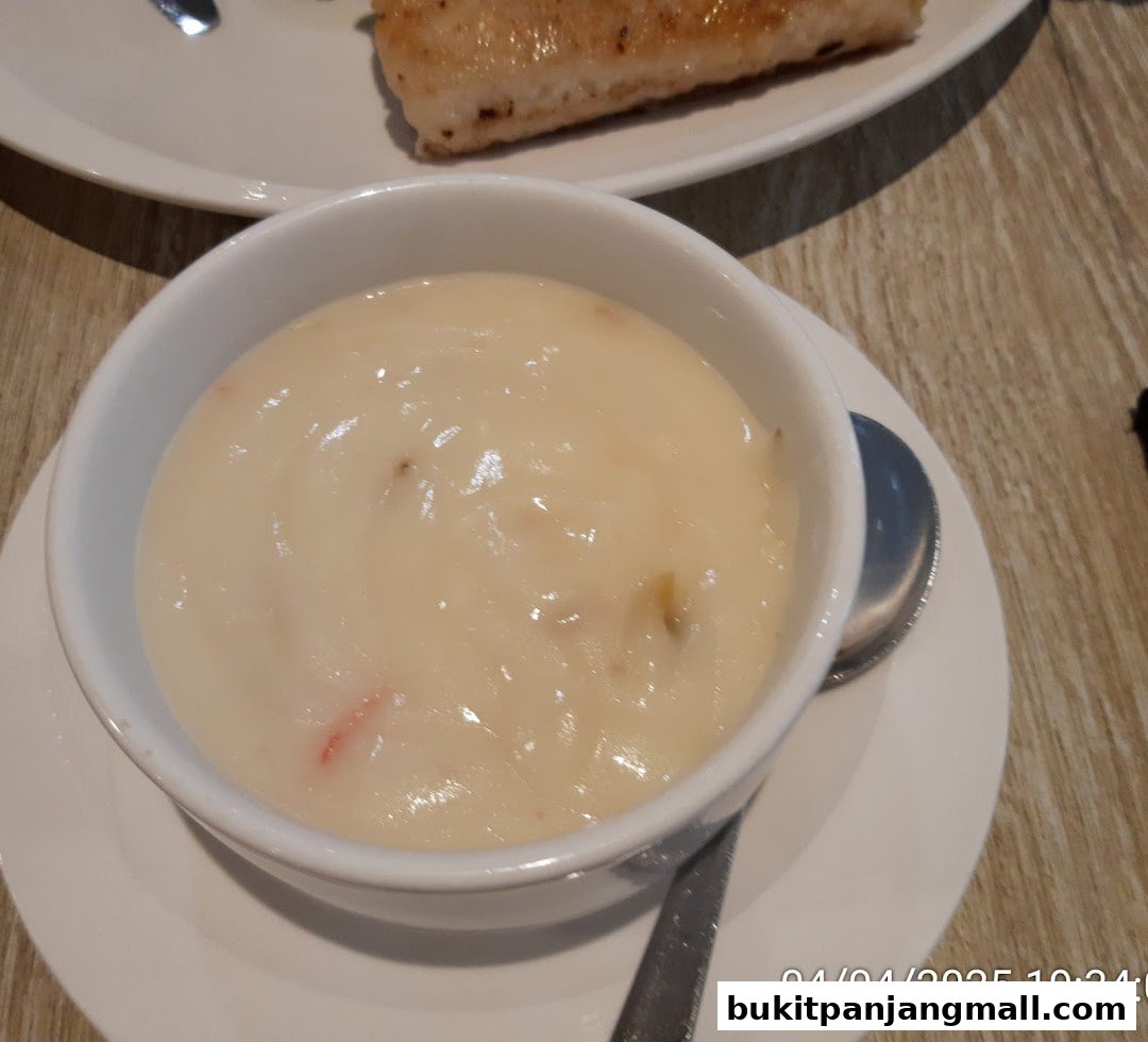 A close-up of a creamy soup in a white bowl with a spoon.