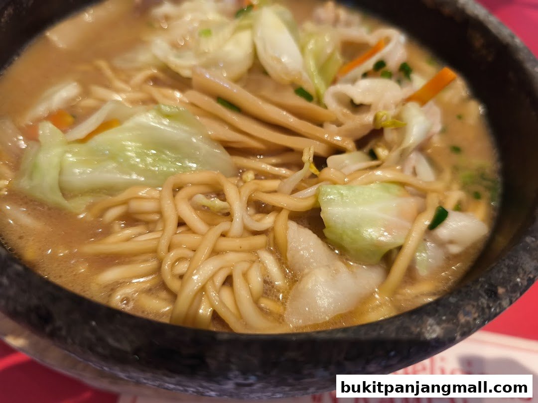 A close-up shot of a steaming bowl of ramen with noodles, cabbage, and other vegetables.