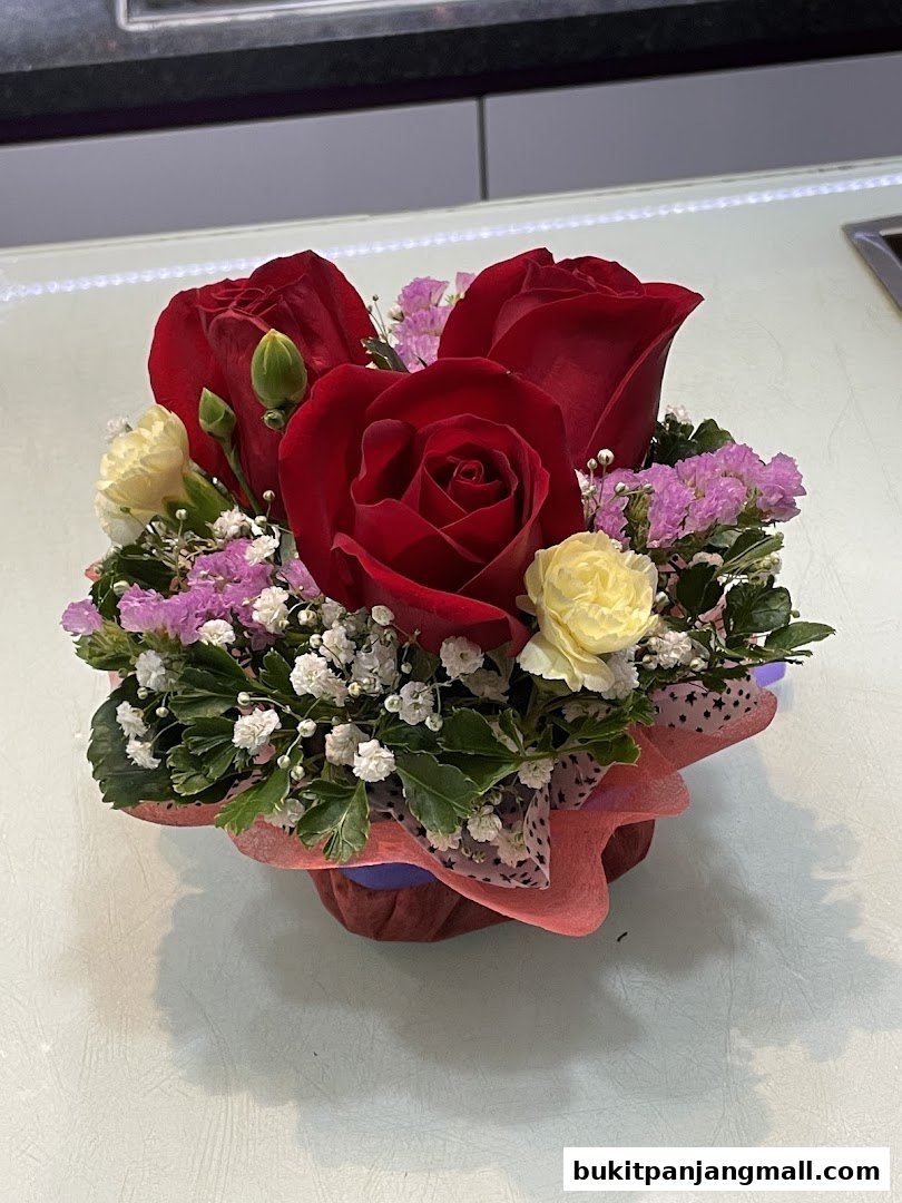 A beautiful arrangement of red roses, yellow carnations, and delicate filler flowers.
