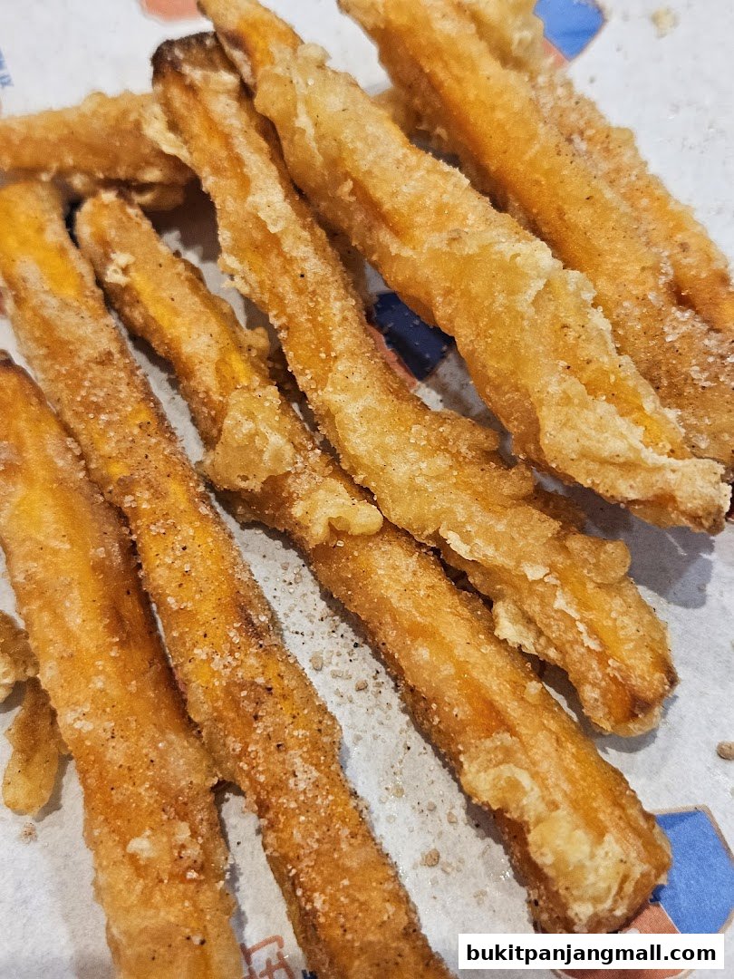 A close-up shot of crispy, golden-brown sweet potato fries dusted with sugar and spices.
