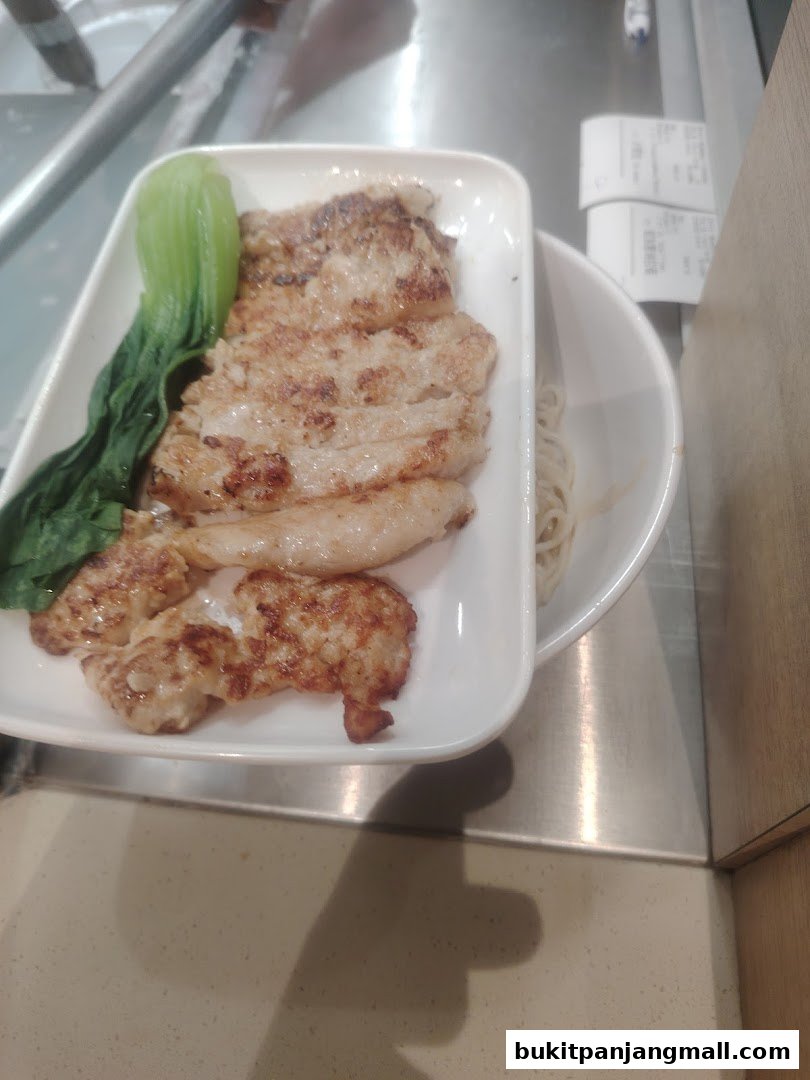 A plate of grilled chicken with bok choy and noodles.