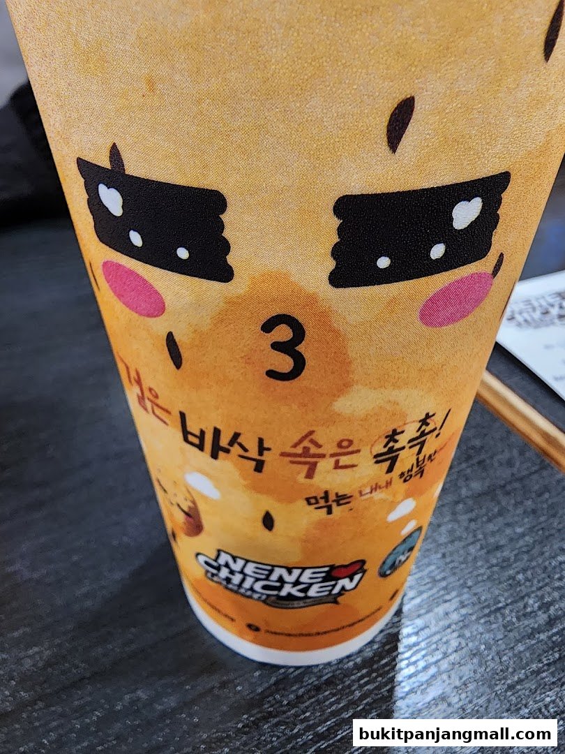 A close-up of a NeNe Chicken cup with a cute cartoon face and Korean text.