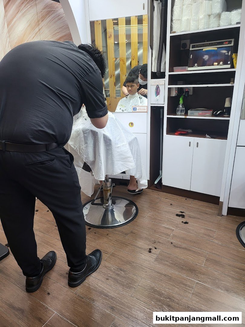 A barber is cutting a young man's hair inside a clean, modern salon.