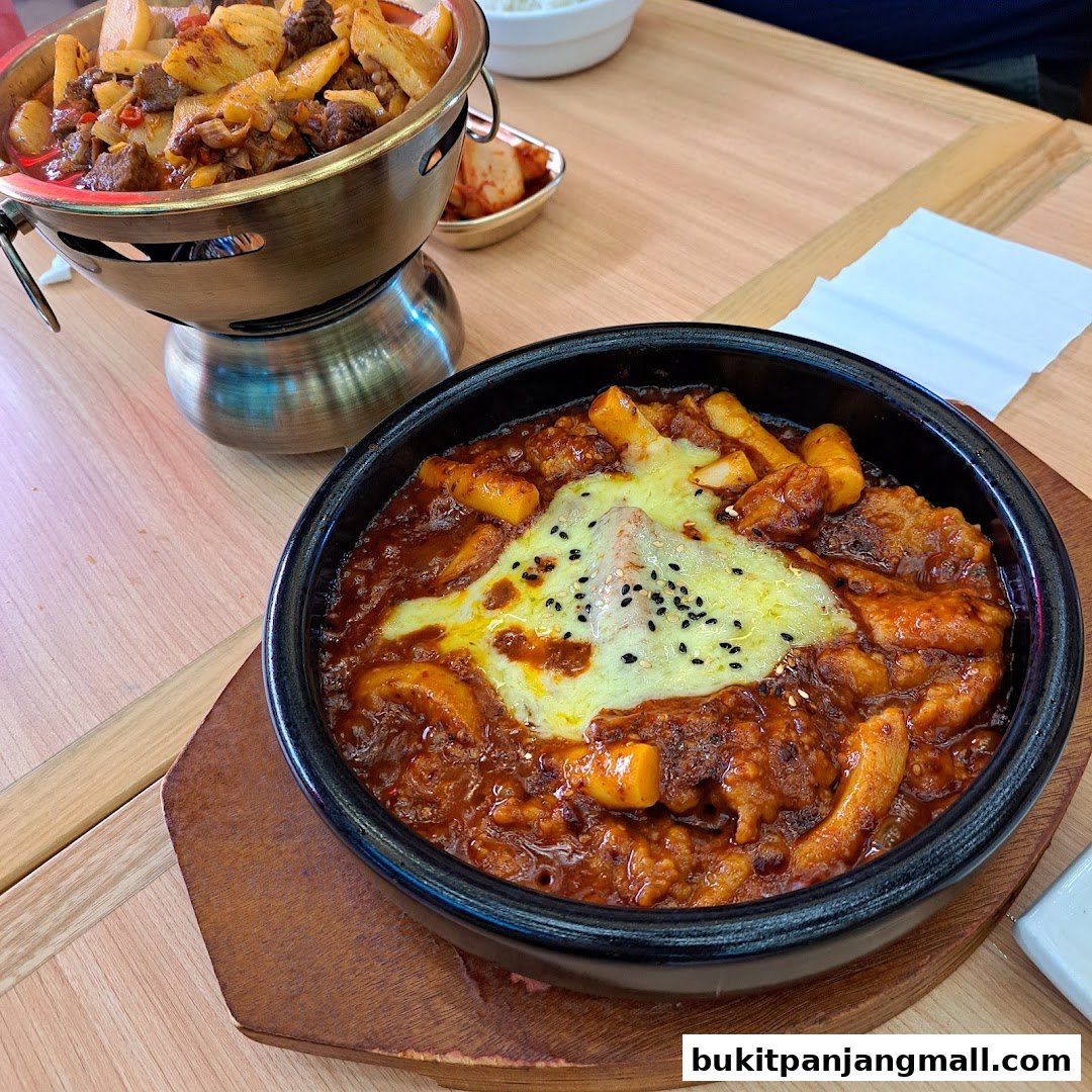 A close-up of two Korean dishes, one with melted cheese and the other with meat and vegetables.