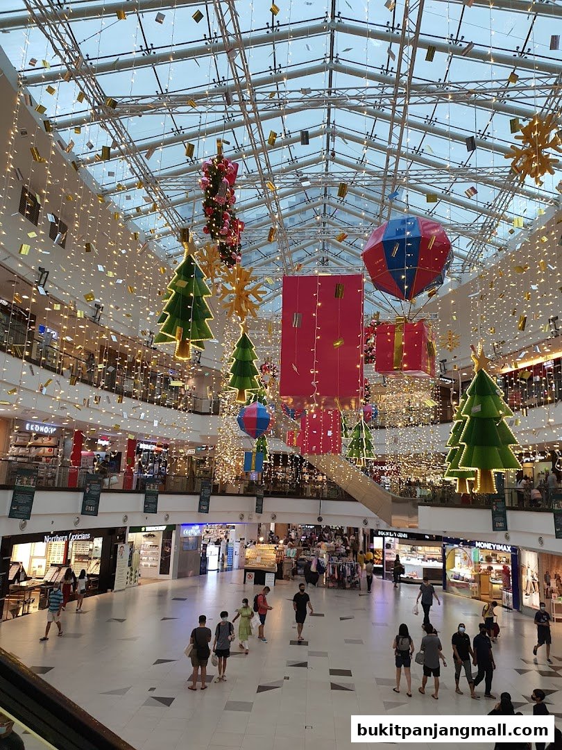 A festive mall interior with Christmas decorations, lights, and shoppers.