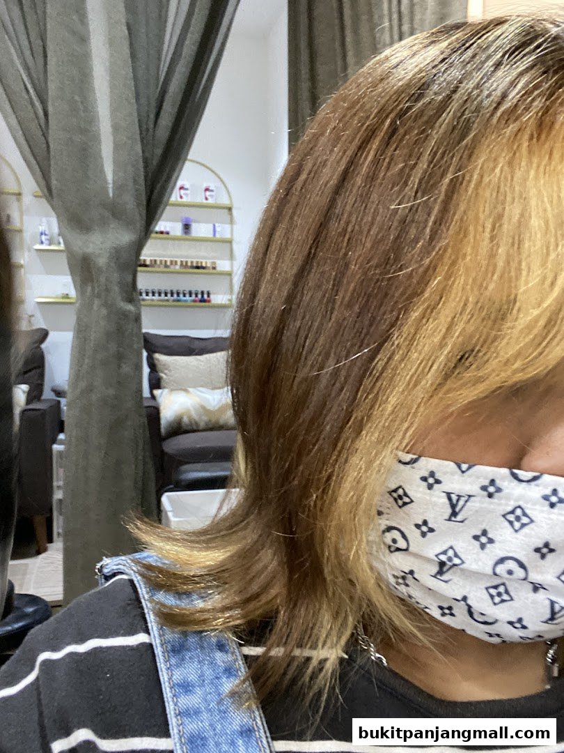 A person with styled hair wearing a mask inside a salon.