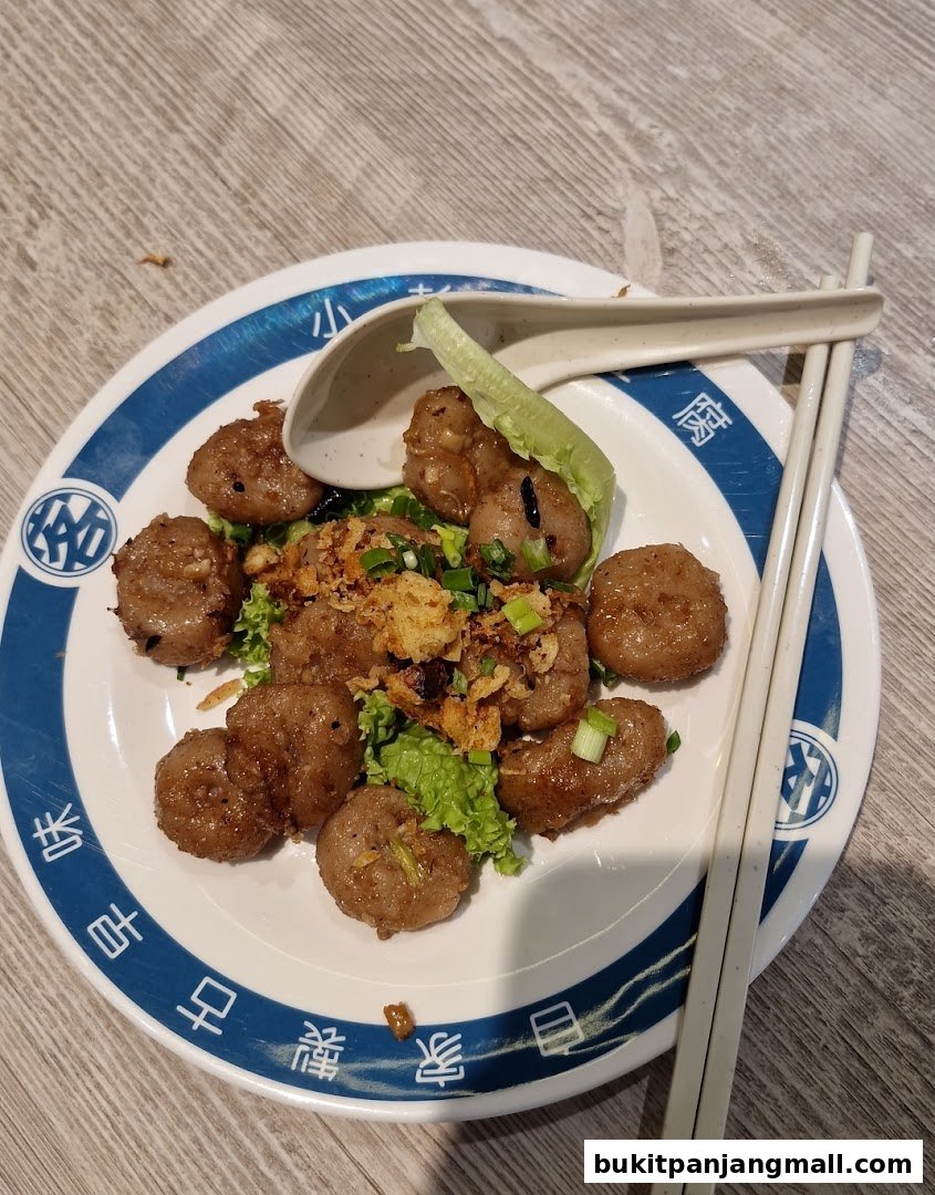 A plate of meatballs with lettuce and crispy toppings, served with chopsticks and a spoon.