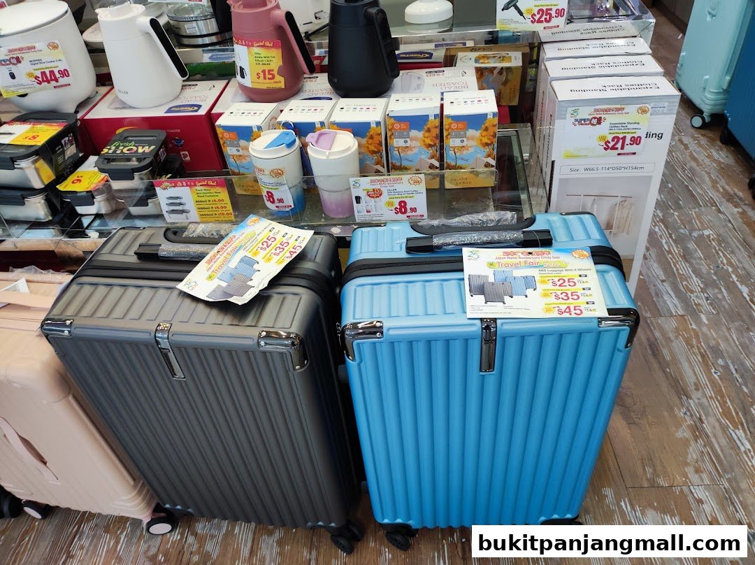 A display of luggage and household items, including kettles and travel cups, with sale signs.