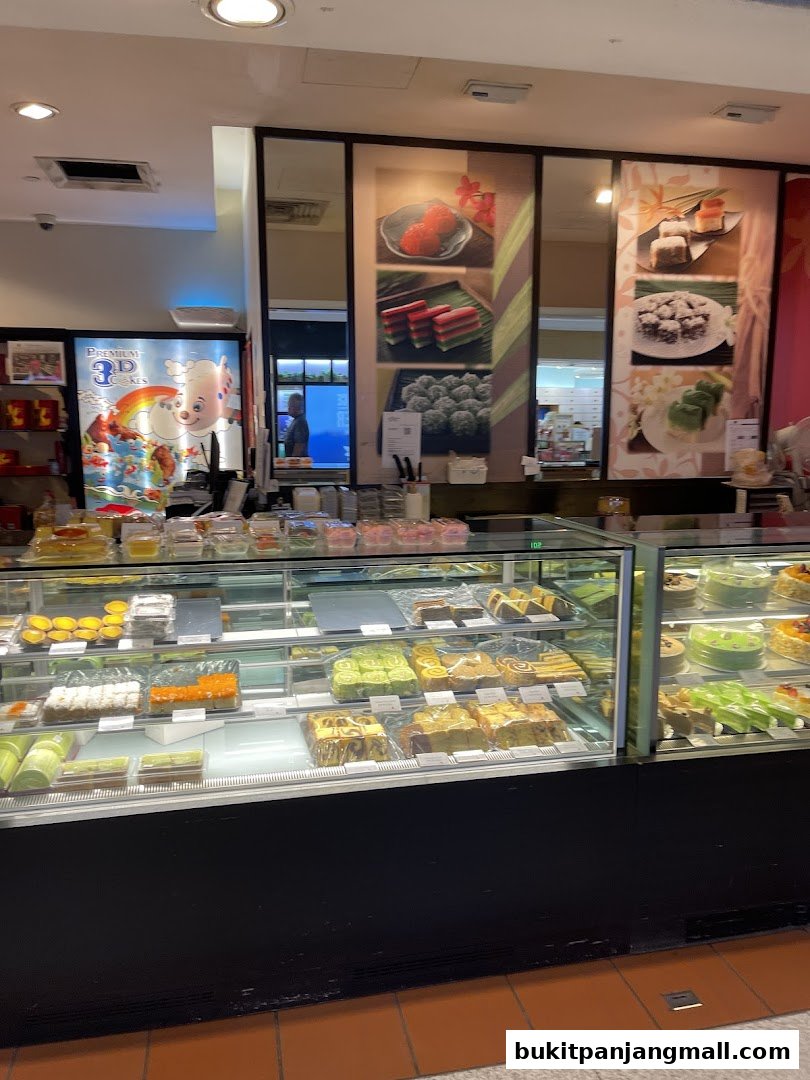 A display case filled with various colorful cakes, pastries, and traditional snacks.